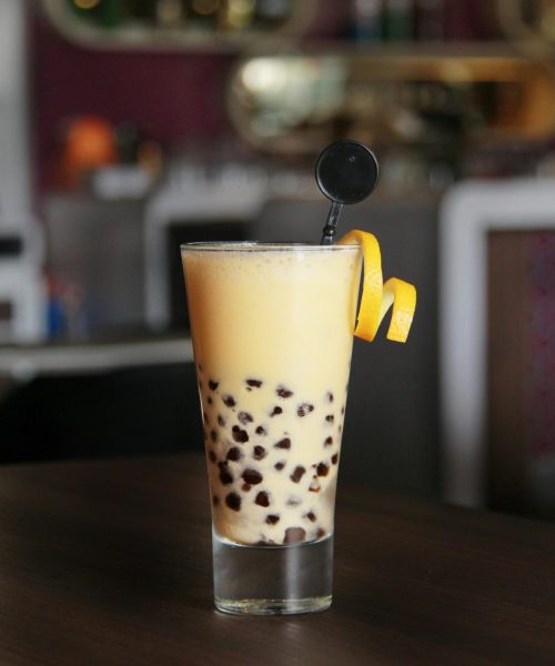 A high glass of bubble tea with citrus garnish in a cozy café setting, perfect for a refreshing break.